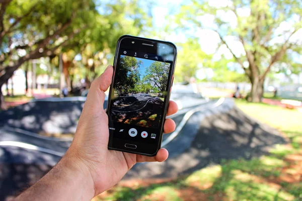 Mao segurando smartphone no parque