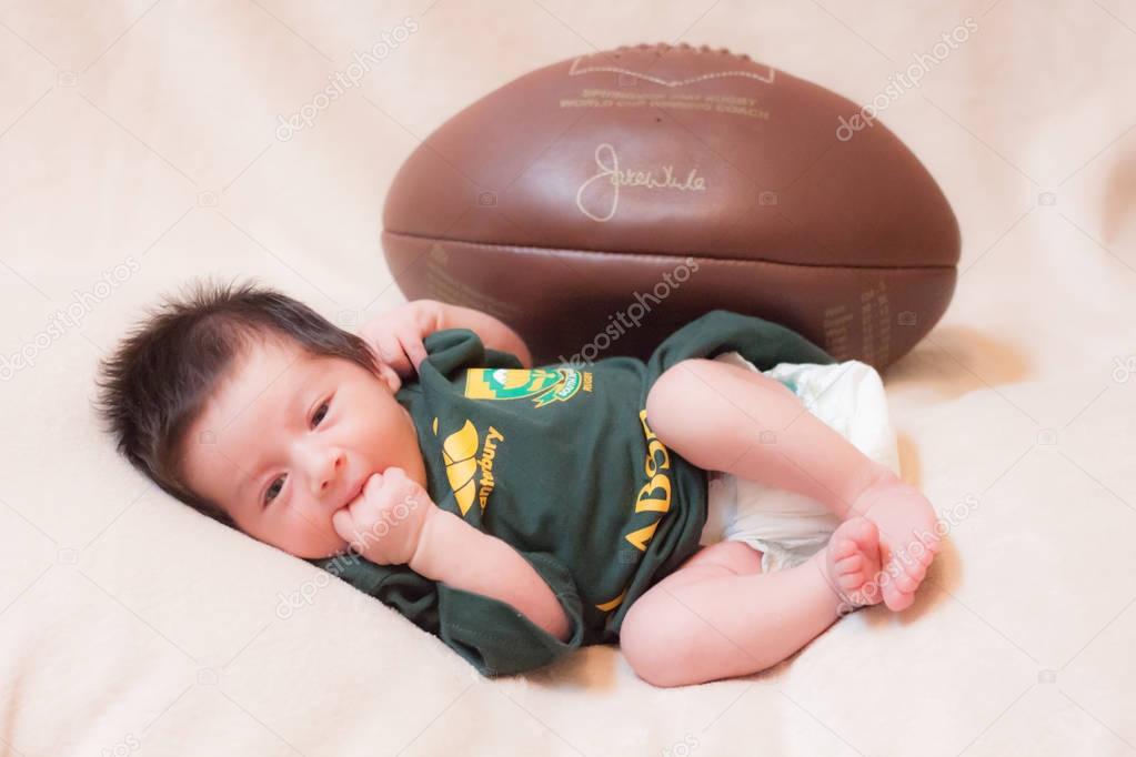 baby with a rugby uniform and ball