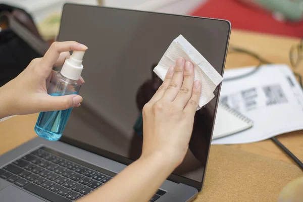 woman is cleaning laptop by alcohol spray