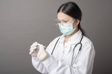 Kadın doktor ateş termometresi kullanıyor.