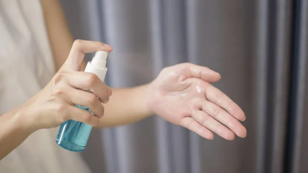 woman is cleaning her hands with alcohol spray