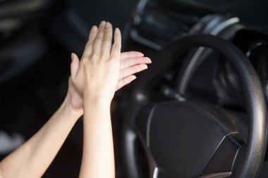 Kadın arabada ellerine dezenfektan sürüyor.