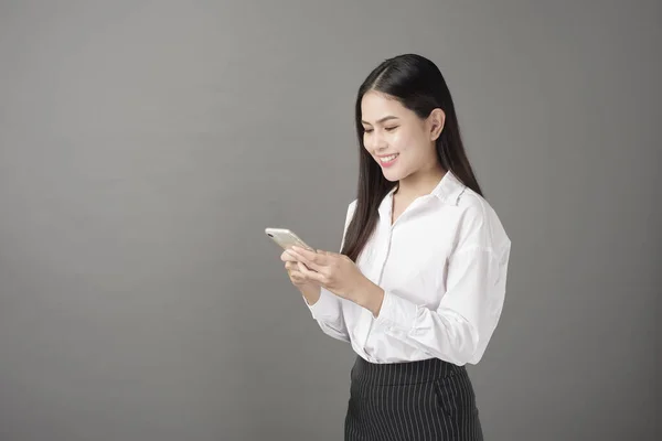 Beautiful woman is using cell phone in studio