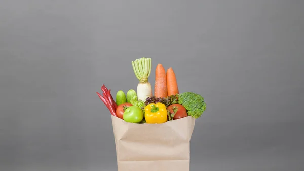 vegetables in grocery bag on studio grey background