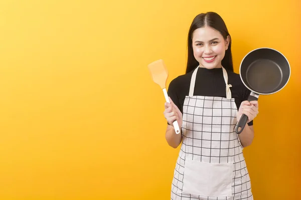 Happy female cook portrait on yellow background