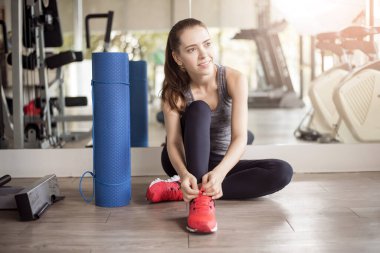 Güzel genç bayan spor ayakkabılarını spor salonunda bağlıyor, sağlıklı bir yaşam tarzı. 