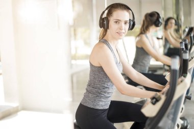 Güzel genç bayan spor salonunda bisiklet egzersizi yapıyor, sağlıklı bir yaşam tarzı. 