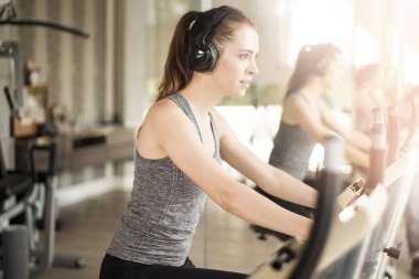 Güzel genç bayan spor salonunda bisiklet egzersizi yapıyor, sağlıklı bir yaşam tarzı. 