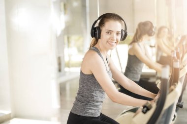 Güzel genç bayan spor salonunda bisiklet egzersizi yapıyor, sağlıklı bir yaşam tarzı. 