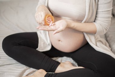 Vitamin hapı içen hamile kadını kapatın. 