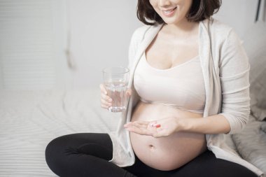 Vitamin hapı içen hamile kadını kapatın. 