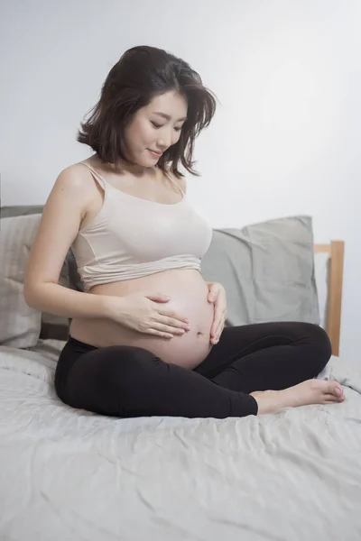 Güzel Asyalı Hamile Kadın Yatağa Otur Karnına Dokun — Stok fotoğraf