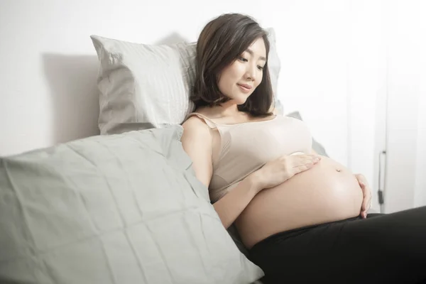 Güzel Asyalı Hamile Kadın Yatağında Uzanmış Koca Göbeğine Dokunuyor — Stok fotoğraf