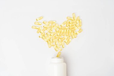 Beyaz arka planda bir yığın sarı vitamin hapı. 