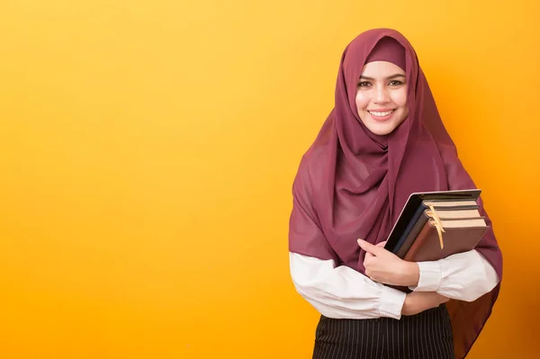 Beautiful University student with hijab portrait on yellow background