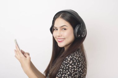 Müzik aşığı kadın beyaz arka planda kulaklıkla eğleniyor. 