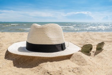 Plajda beyaz şapka ve güneş gözlüğü, yaz konsepti. 
