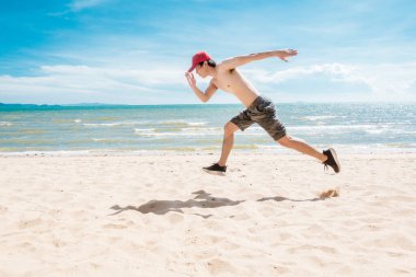 Kaslı adam sahilde koşuyor. 