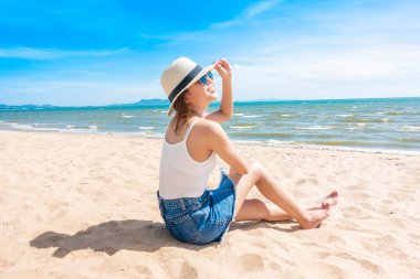 Güzel bir kadın sahilde oturuyor. 