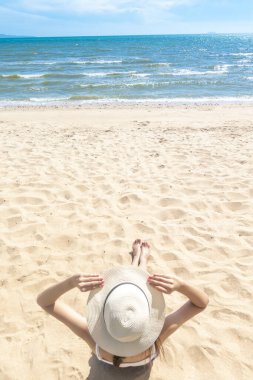 Güzel bir kadın sahilde oturuyor. 