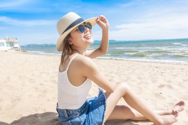 Güzel bir kadın sahilde oturuyor. 