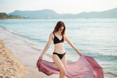 Siyah bikinili güzel bir kadın sahilde yürüyor. 