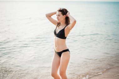 Siyah bikinili güzel bir kadın sahilde yürüyor. 