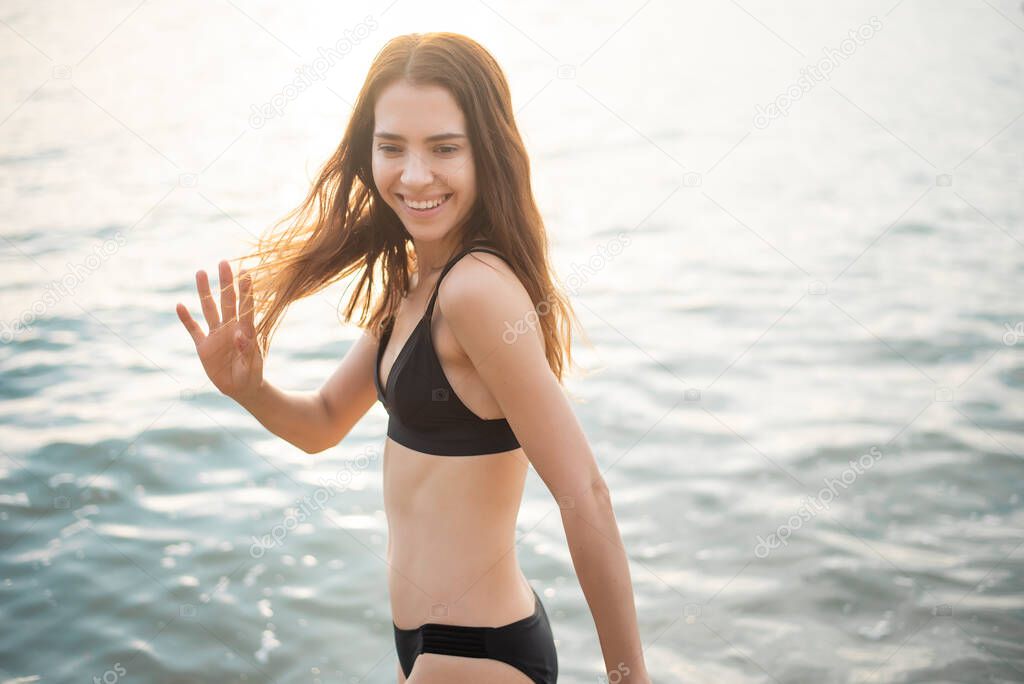 Beautiful woman in black bikini is enjoying with sea water on the beach 