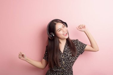 Müzik aşığı kadın pembe arka planda kulaklıkla eğleniyor. 