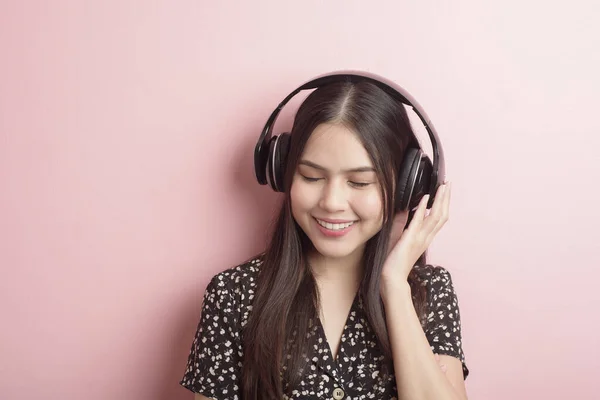音乐爱好者女人喜欢带着粉色背景的耳机 — 图库照片