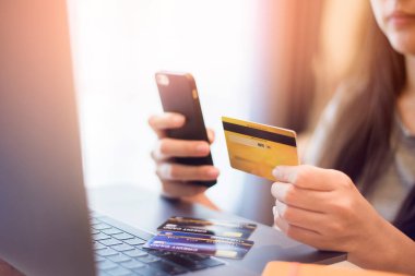 Kadının eli kredi kartını tutuyor, internetten alışveriş yapıyor. 