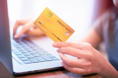 Kadının eli kredi kartını tutuyor, internetten alışveriş yapıyor. 