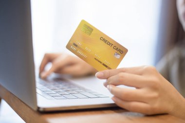 Kadının eli kredi kartını tutuyor, internetten alışveriş yapıyor. 