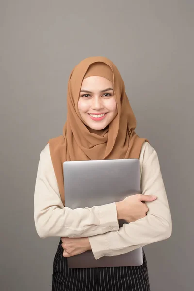 戴头巾的漂亮女人的画像是带着灰色背景的笔记本电脑 — 图库照片