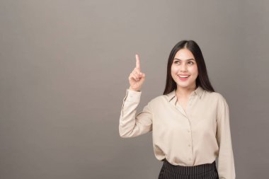 Güzel iş kadınının portresi gri arka planda bir şey gösteriyor. 