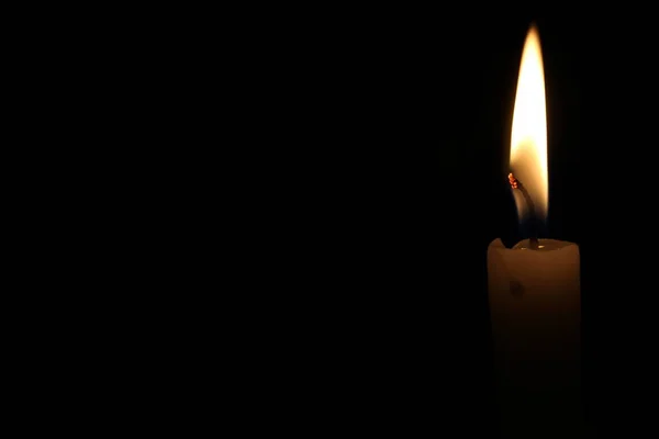 一支点着的蜡烛在黑色的背景下闪闪发光 — 图库照片