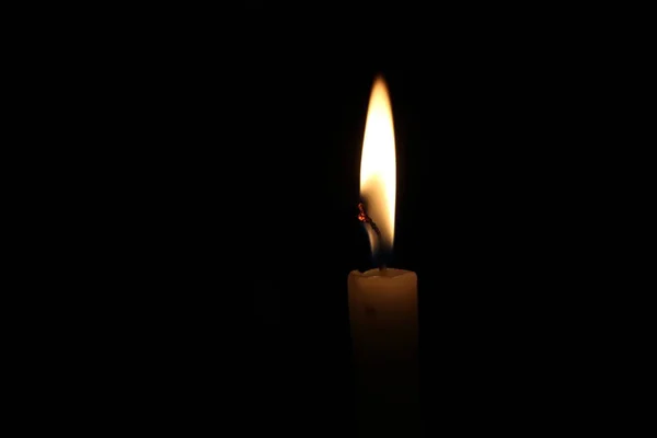一支点着的蜡烛在黑色的背景下闪闪发光 — 图库照片