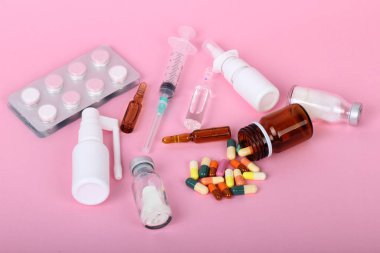 Pembe arka planda izole tıbbi şişeler, ilaçlar ve