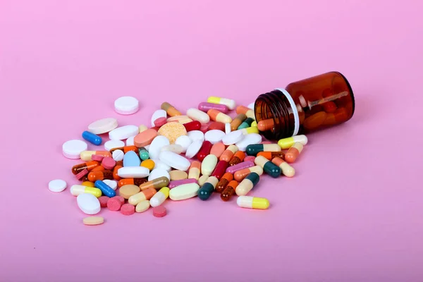 Pembe arka planda izole tıbbi şişeler, ilaçlar ve