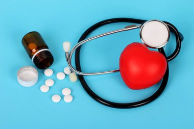 Kalp ve steteskop mavi arka planda tıbbi ilaçlarla 