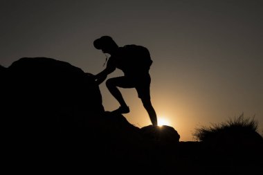 Günbatımında tırmanan bir adamın silueti