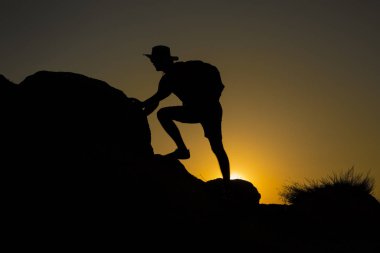 Günbatımında tırmanan bir adamın silueti