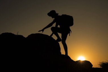 Günbatımında tırmanan bir adamın silueti
