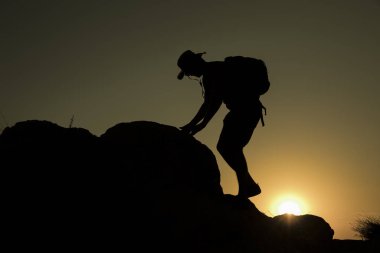 Günbatımında tırmanan bir adamın silueti