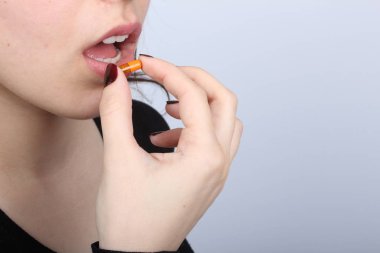 Ağzına hap tıkan genç kadın.