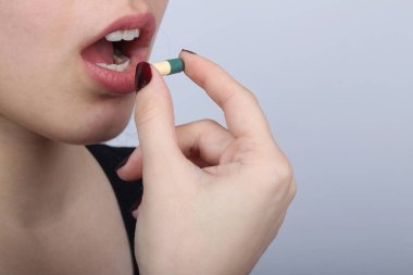 Ağzına hap tıkan genç kadın.