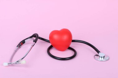 Stetoskop ve kalp pembe arka planda izole edilmiş.