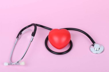 Stetoskop ve kalp pembe arka planda izole edilmiş.