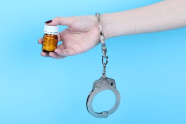 Mavi arka planda elleri kelepçeli haplar ve tabletler