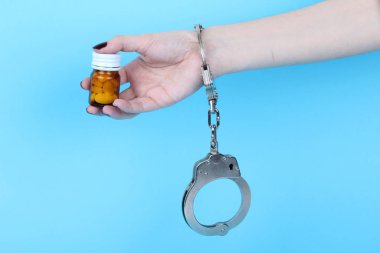 Mavi arka planda elleri kelepçeli haplar ve tabletler